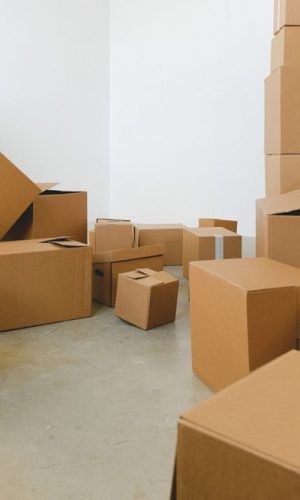 Heaps of different cardboard boxes on floor in rented house in daytime on white background