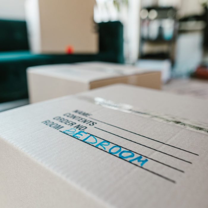 Packed cardboard box labeled 'Bedroom' indoors, ready for moving.
