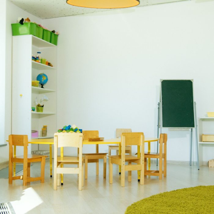 A well-lit, colorful kindergarten classroom with chairs, tables, and educational materials.